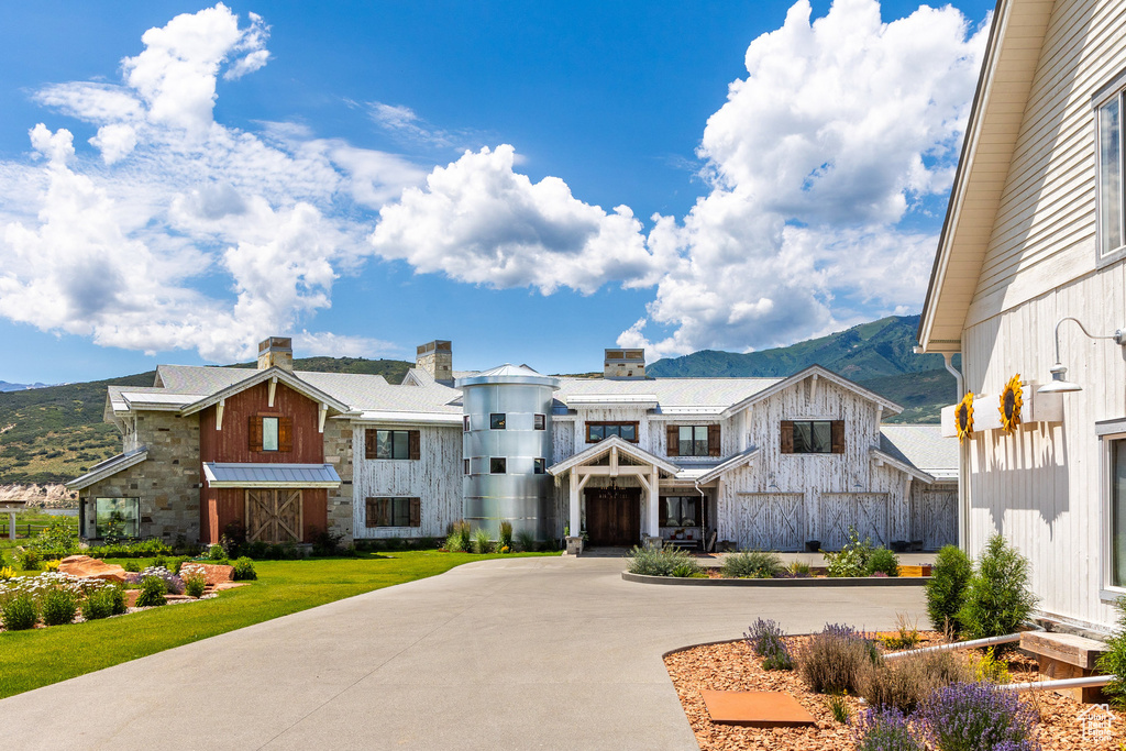 View of front facade featuring a mountain view, curved driveway, and board and batten siding