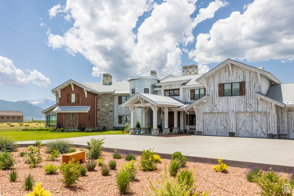 View of front of house with a garage, driveway, a mountain view, board and batten siding, and a chimney