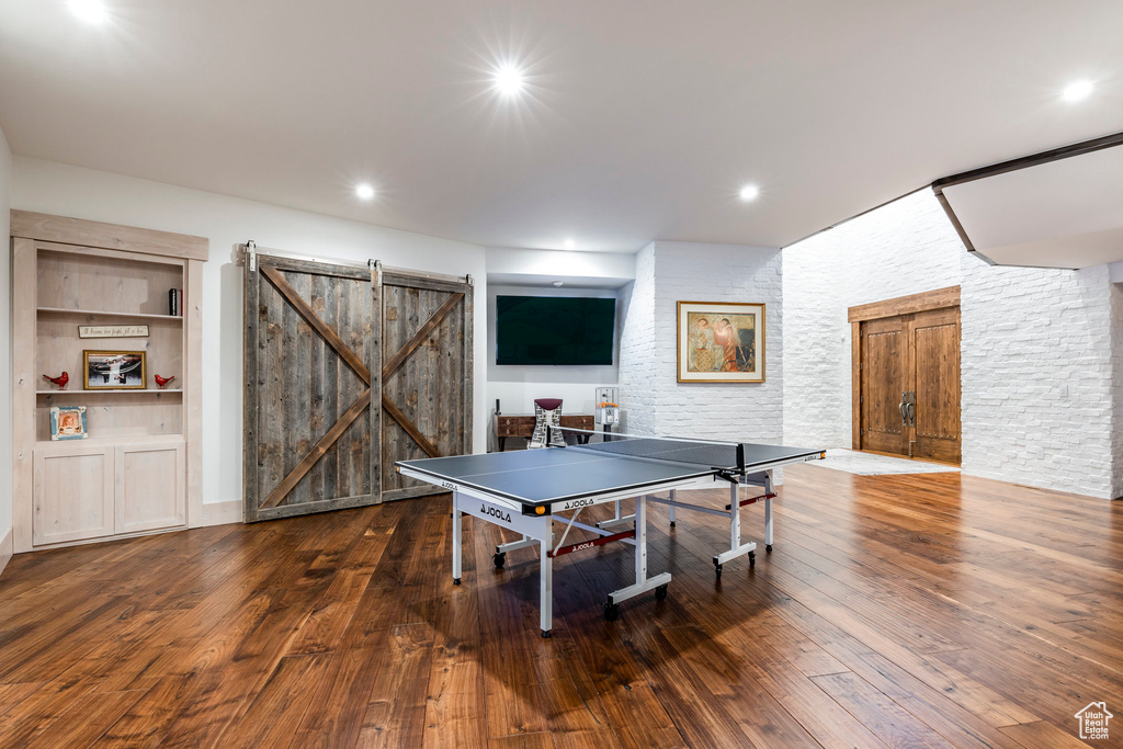 Game room featuring a barn door, hardwood / wood-style floors, built in features, and recessed lighting