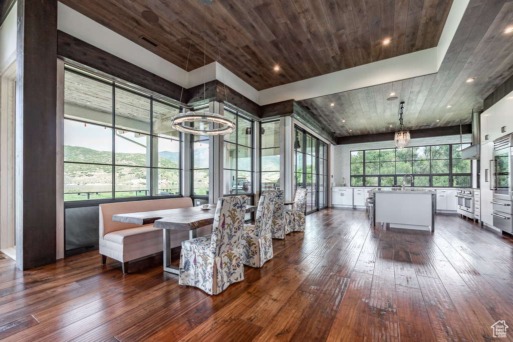 Dining space featuring dark wood-type flooring, wood ceiling, recessed lighting, a chandelier, and breakfast area