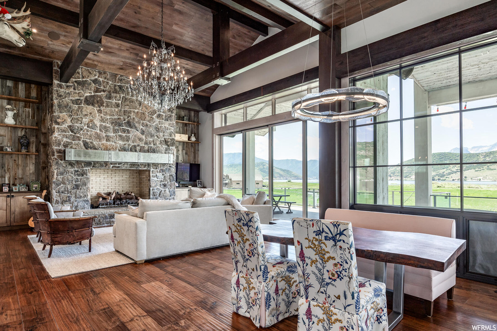 Dining area featuring an inviting chandelier, a mountain view, a fireplace, dark hardwood / wood-style floors, and beamed ceiling