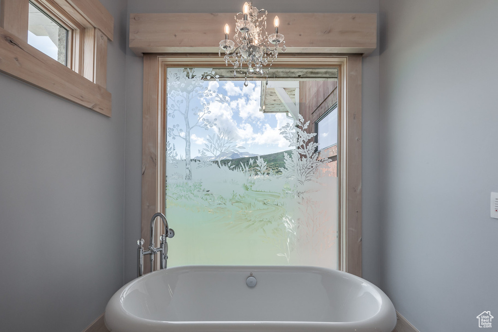 Bathroom featuring a chandelier, healthy amount of natural light, and a freestanding tub