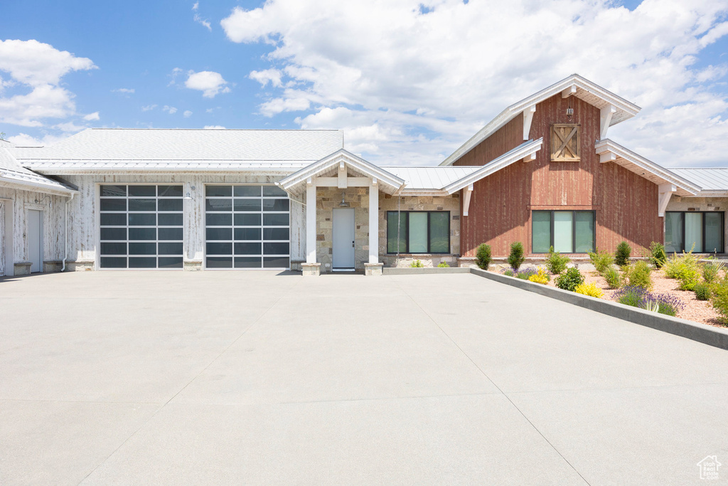 View of front of home with metal roof, driveway, and an attached garage