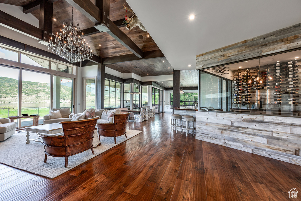 Living room featuring a chandelier, hardwood / wood-style flooring, beam ceiling, healthy amount of natural light, and high vaulted ceiling