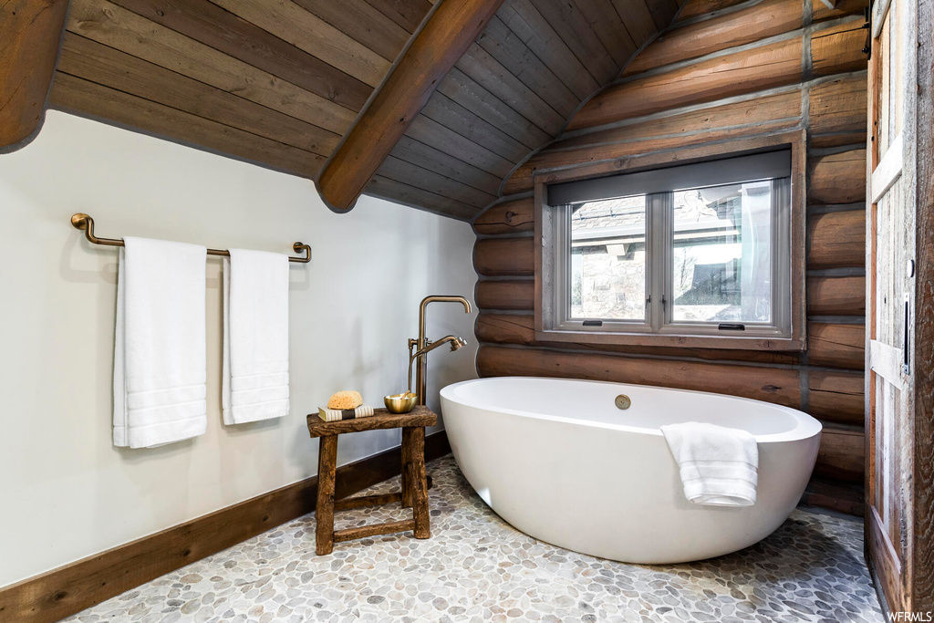 Bathroom with wooden ceiling, tile flooring, log walls, lofted ceiling, and a washtub