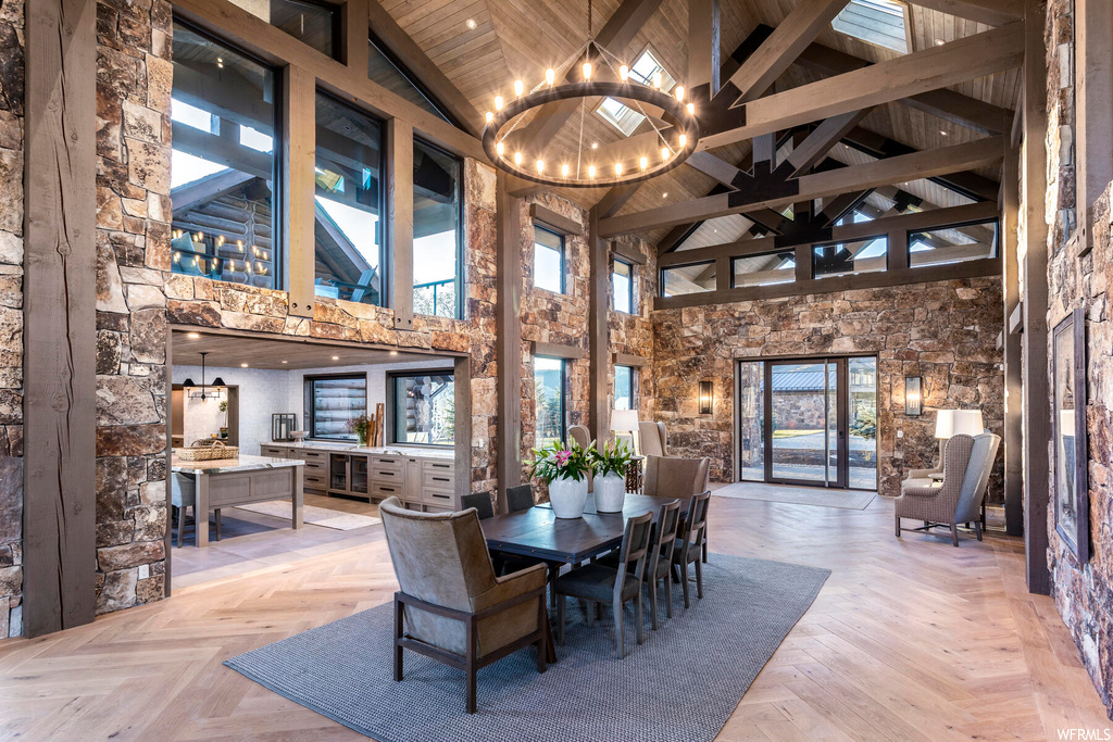 Dining space featuring an inviting chandelier, light parquet floors, high vaulted ceiling, and beam ceiling