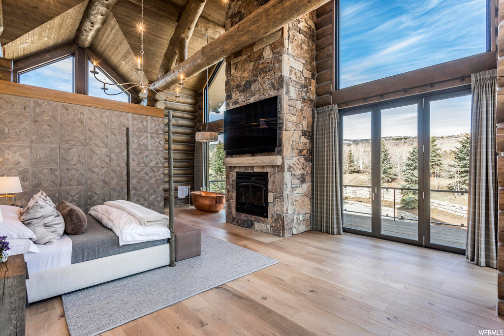 Unfurnished bedroom featuring a stone fireplace, log walls, and light hardwood / wood-style flooring
