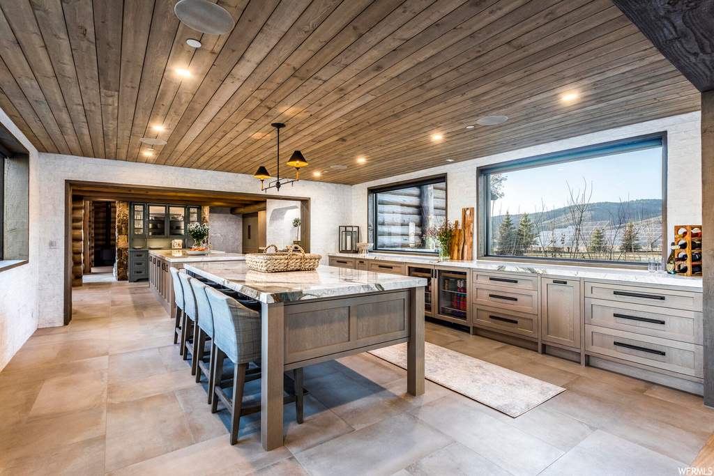 Kitchen with wooden ceiling, a kitchen island, hanging light fixtures, and light tile flooring