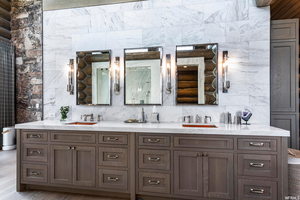 Bathroom with tasteful backsplash, dual vanity, and hardwood / wood-style floors