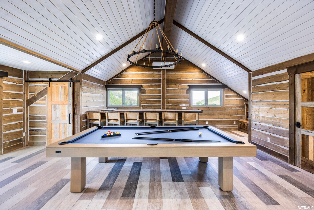 Game room with pool table, wood walls, a wealth of natural light, and light hardwood / wood-style floors