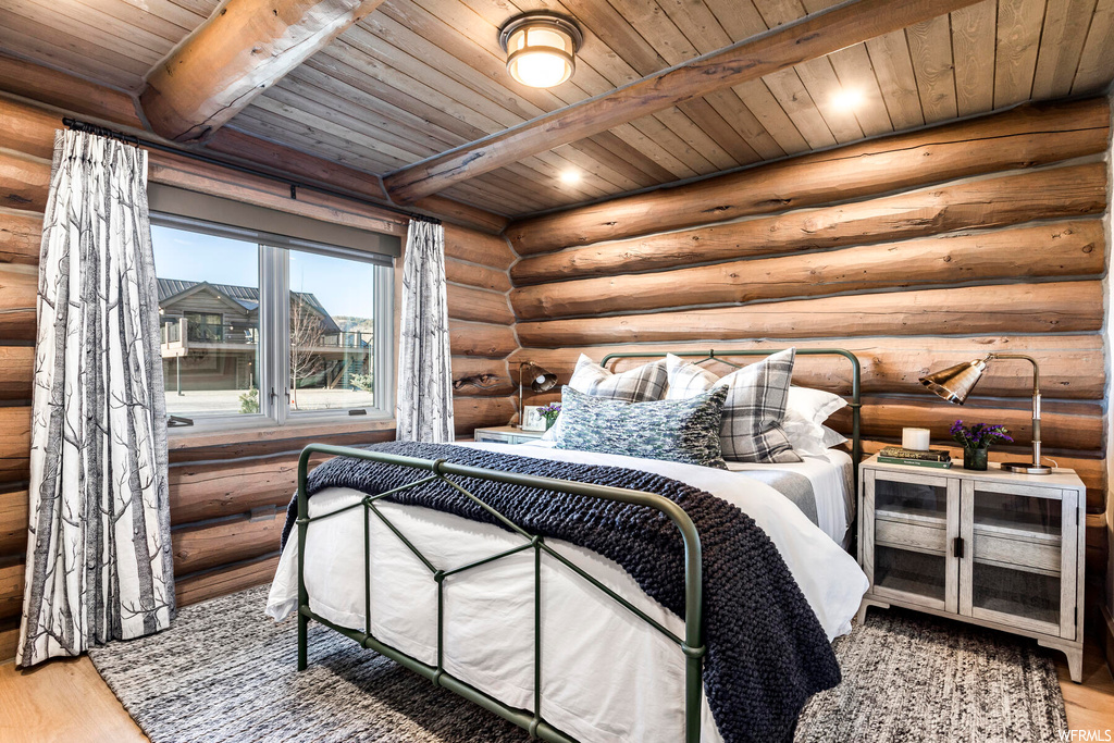 Bedroom featuring log walls, wood ceiling, light hardwood / wood-style floors, and beam ceiling