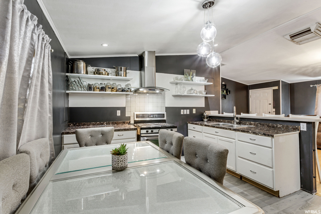 kitchen with range hood, range oven, stainless steel finishes, white cabinetry, and light floors