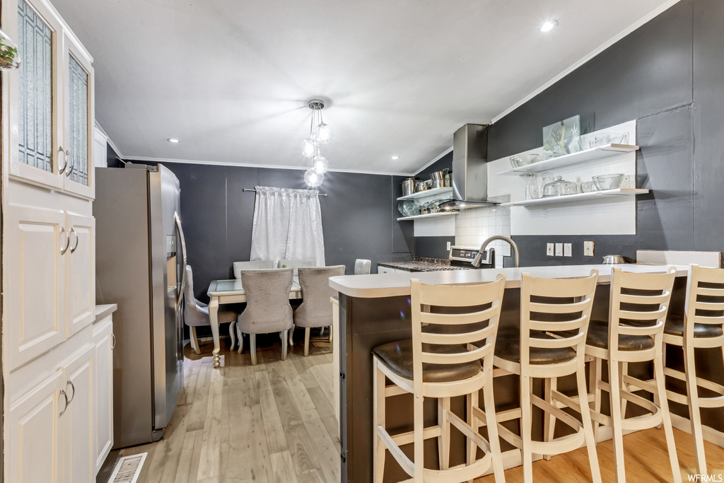 kitchen featuring range hood, refrigerator, light countertops, and light hardwood floors