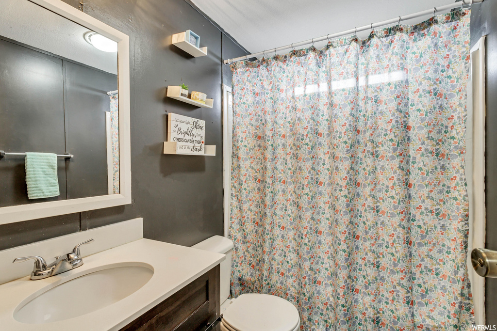bathroom with shower curtain, mirror, toilet, and vanity