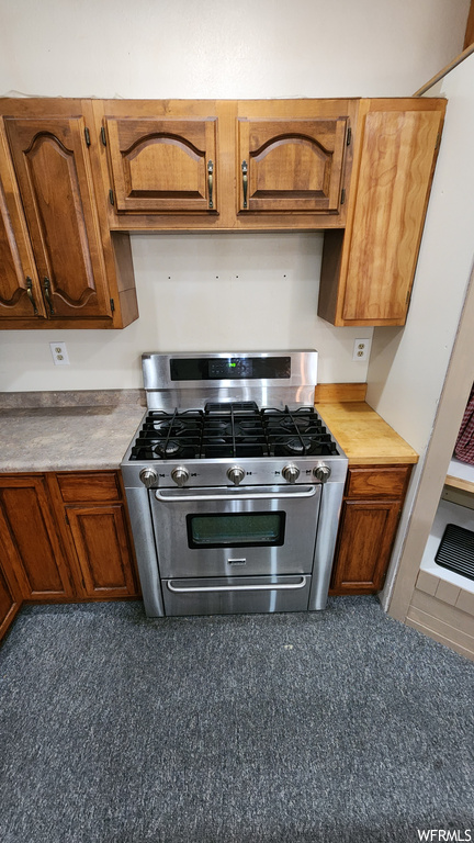 Kitchen with stainless steel finishes, gas range oven, and light countertops