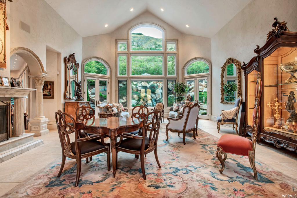 dining space featuring natural light, tile flooring, a high ceiling, and vaulted ceiling