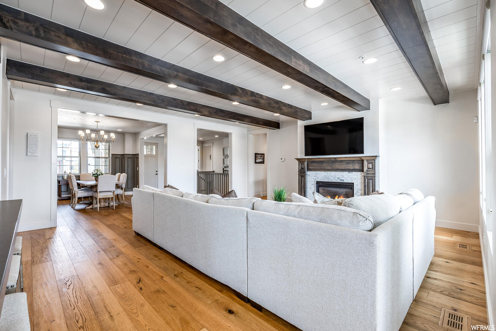 Living room with natural light, wood-type flooring, a fireplace, wood beam ceiling, and TV
