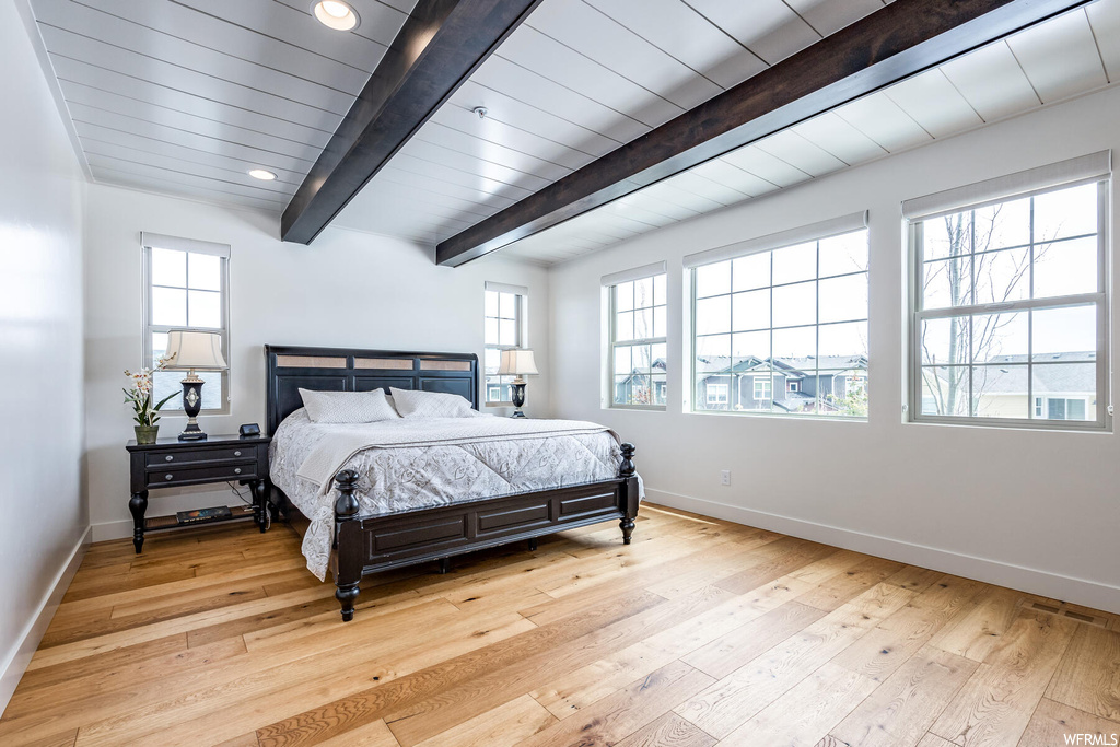 Hardwood floored bedroom featuring natural light and beamed ceiling