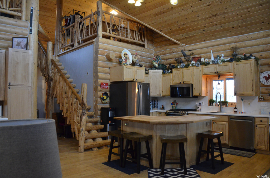 Kitchen featuring a breakfast bar, microwave, range oven, stainless steel dishwasher, light countertops, and light parquet floors