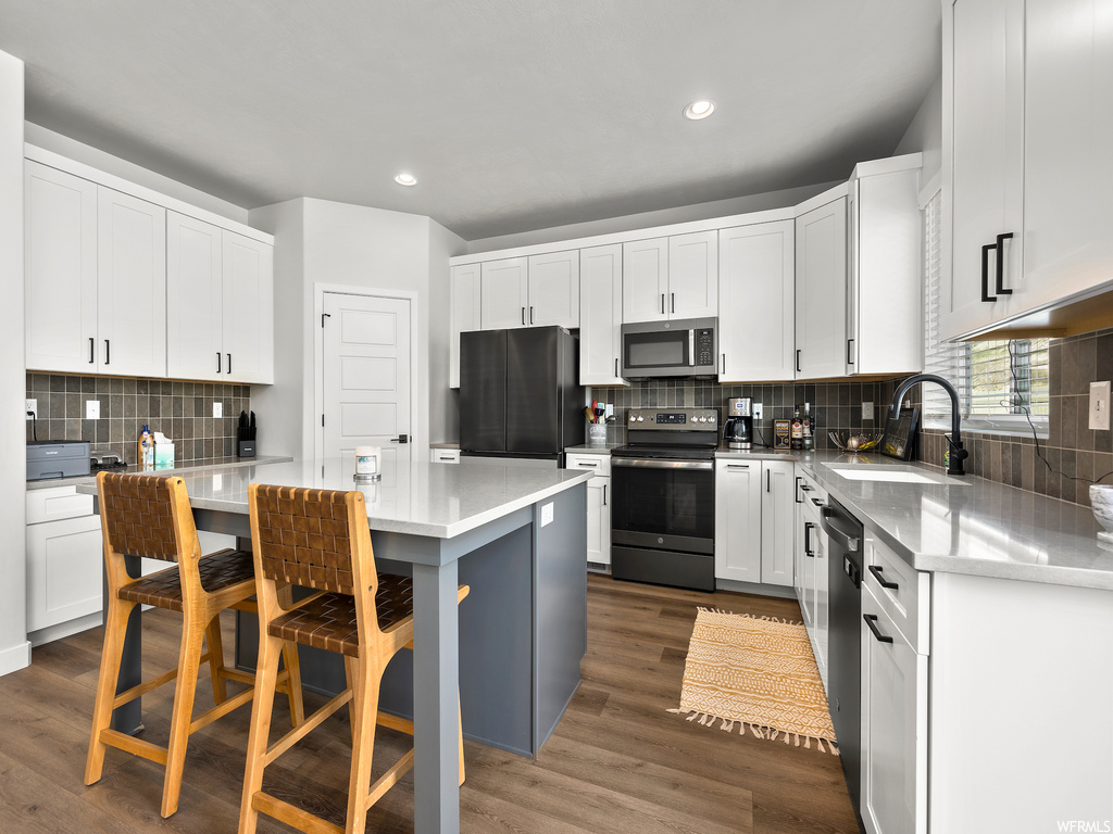 kitchen featuring refrigerator, microwave, range oven, dishwasher, light countertops, white cabinetry, and light parquet floors