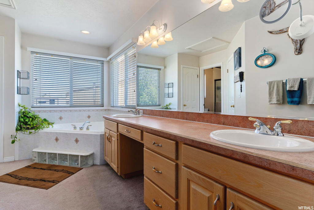 bathroom featuring natural light, his and hers large vanity, a bathtub, and multiple mirrors