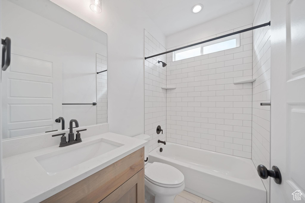 Full bathroom featuring vanity, toilet, tiled shower / bath, and tile floors