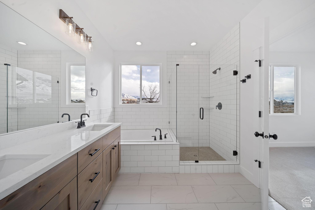 Bathroom featuring dual bowl vanity, shower with separate bathtub, and tile flooring
