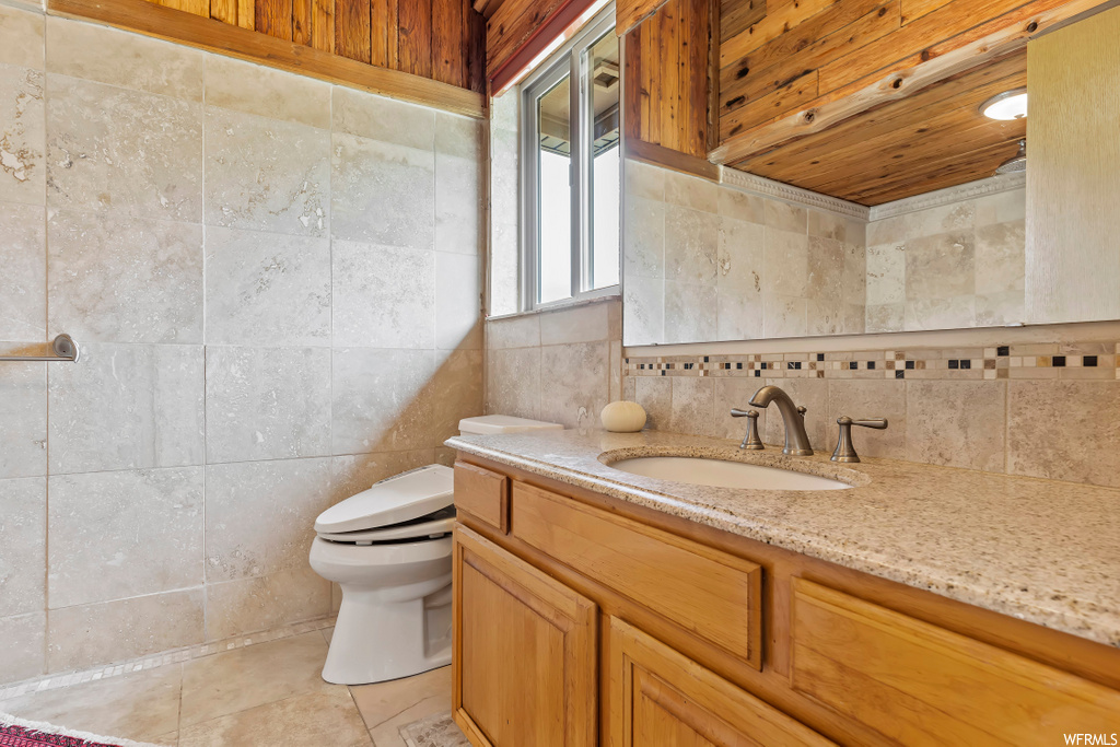 Half bath featuring tile floors, toilet, mirror, and large vanity