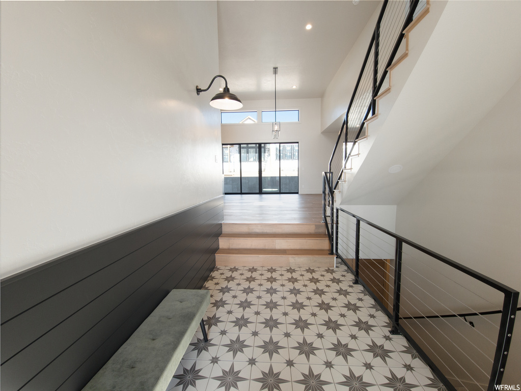 Stairway featuring a high ceiling and light tile floors