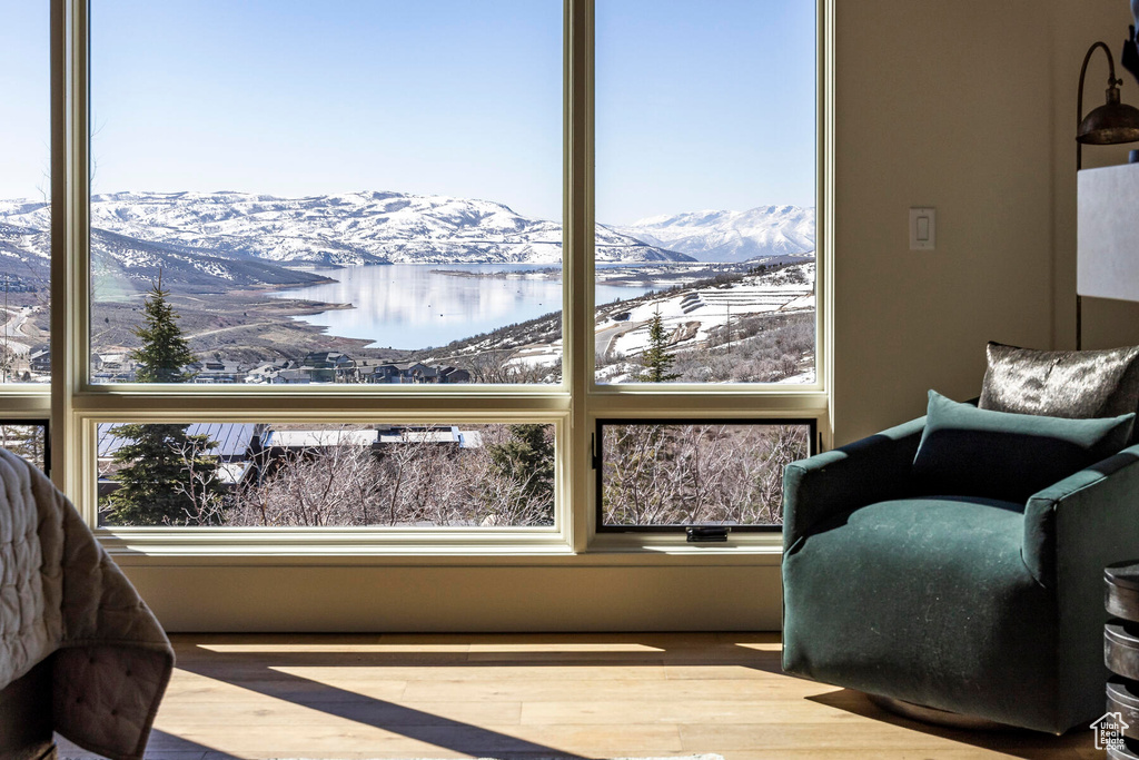 Sitting room with hardwood / wood-style flooring, a healthy amount of sunlight, and a water and mountain view