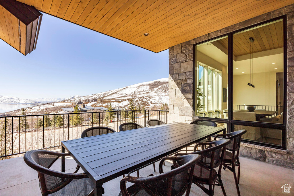 Snow covered back of property with a patio and a mountain view