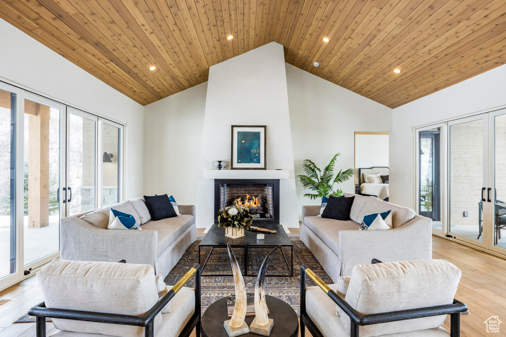 Living room featuring high vaulted ceiling, light hardwood / wood-style floors, a healthy amount of sunlight, and wood ceiling