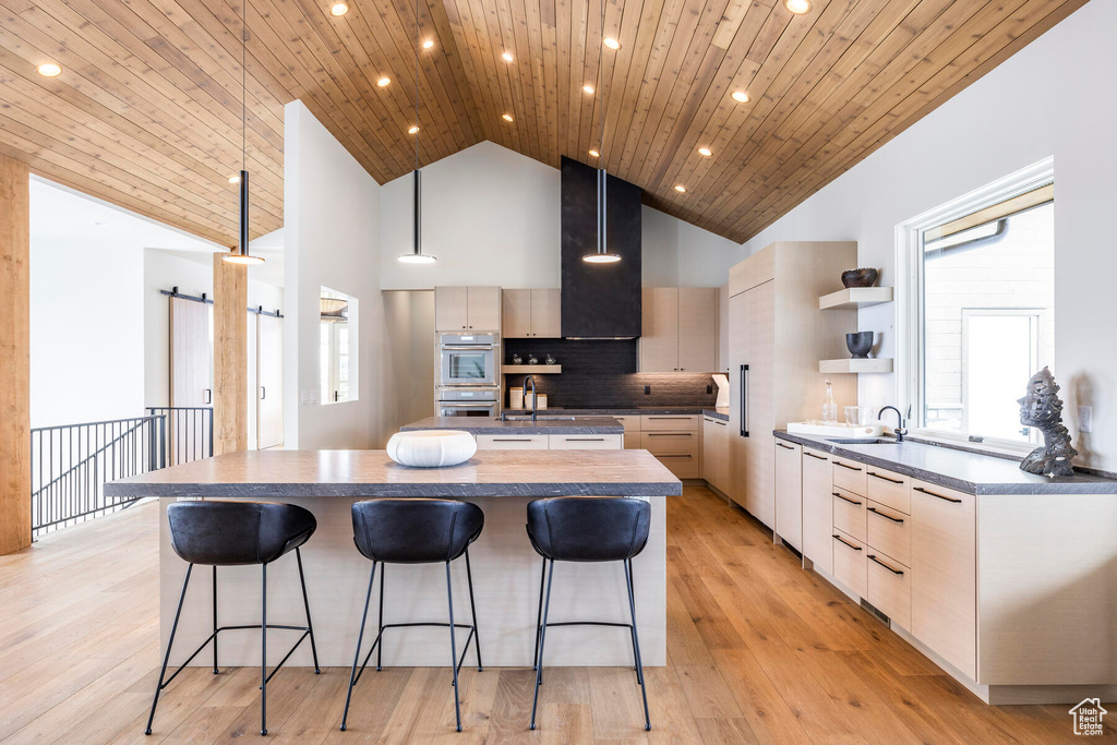 Kitchen featuring a center island, light hardwood / wood-style floors, backsplash, wood ceiling, and hanging light fixtures