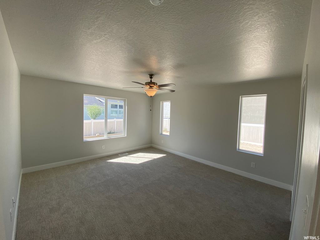 Carpeted spare room with a textured ceiling and ceiling fan