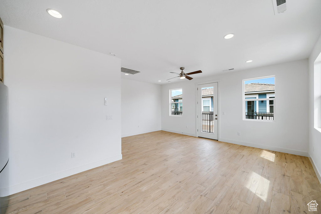 Empty room with ceiling fan and light hardwood / wood-style flooring