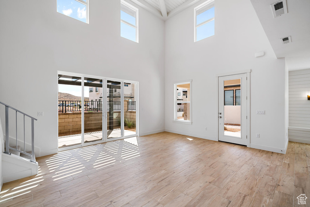 Interior space with a towering ceiling, a wealth of natural light, and light hardwood / wood-style flooring