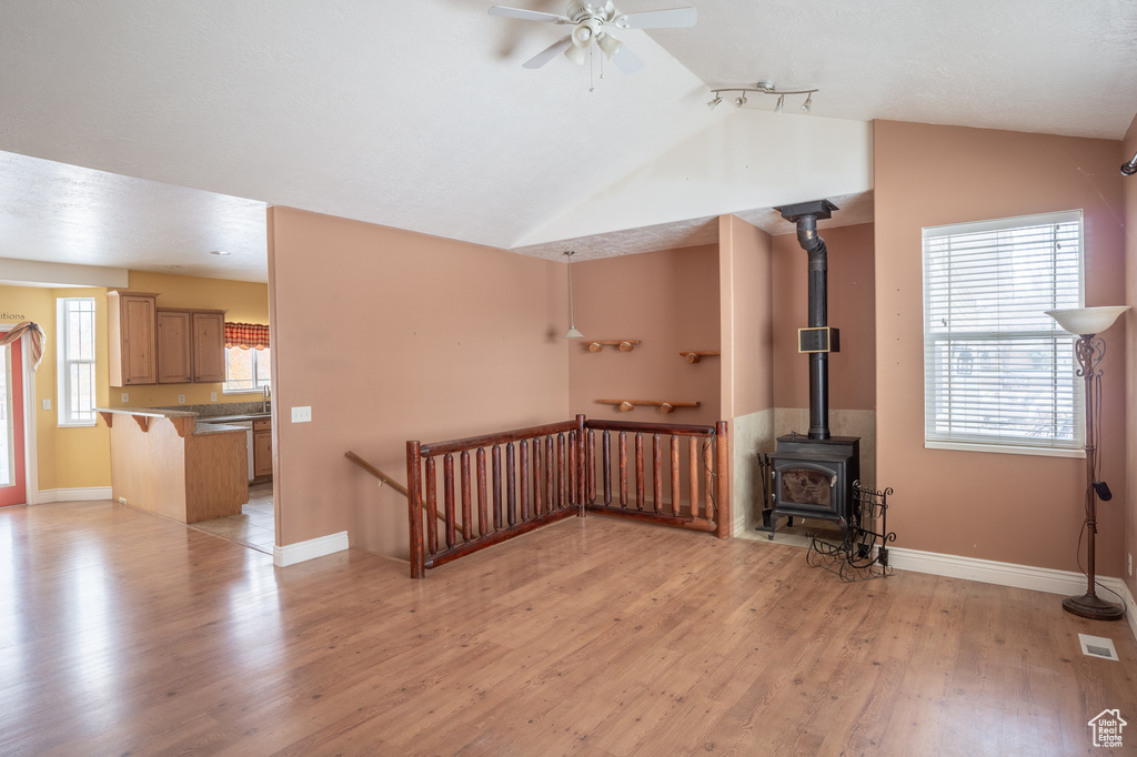 Spare room with light hardwood / wood-style floors, ceiling fan, and a wood stove