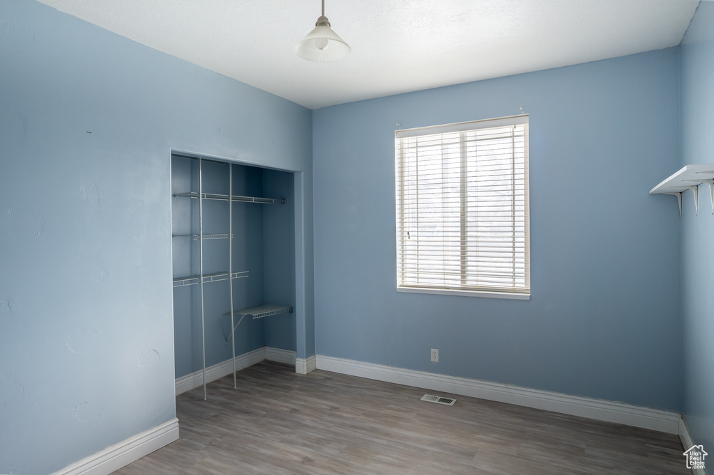 Unfurnished bedroom featuring multiple windows, a closet, and hardwood / wood-style floors