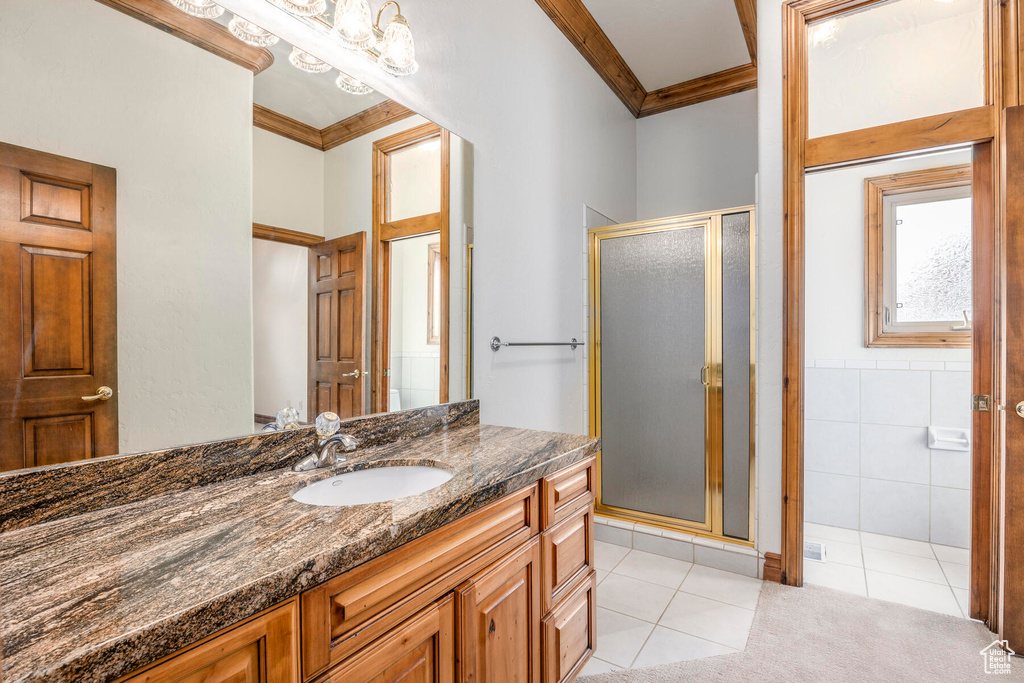 Bathroom with an enclosed shower, tile walls, tile floors, oversized vanity, and ornamental molding