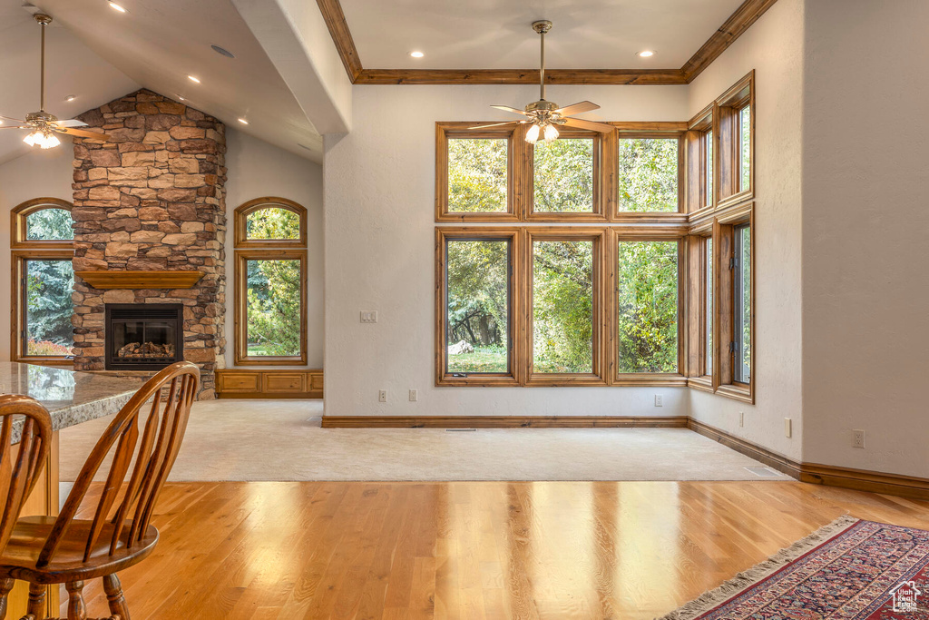 Interior space featuring a stone fireplace, light hardwood / wood-style floors, ceiling fan, and high vaulted ceiling