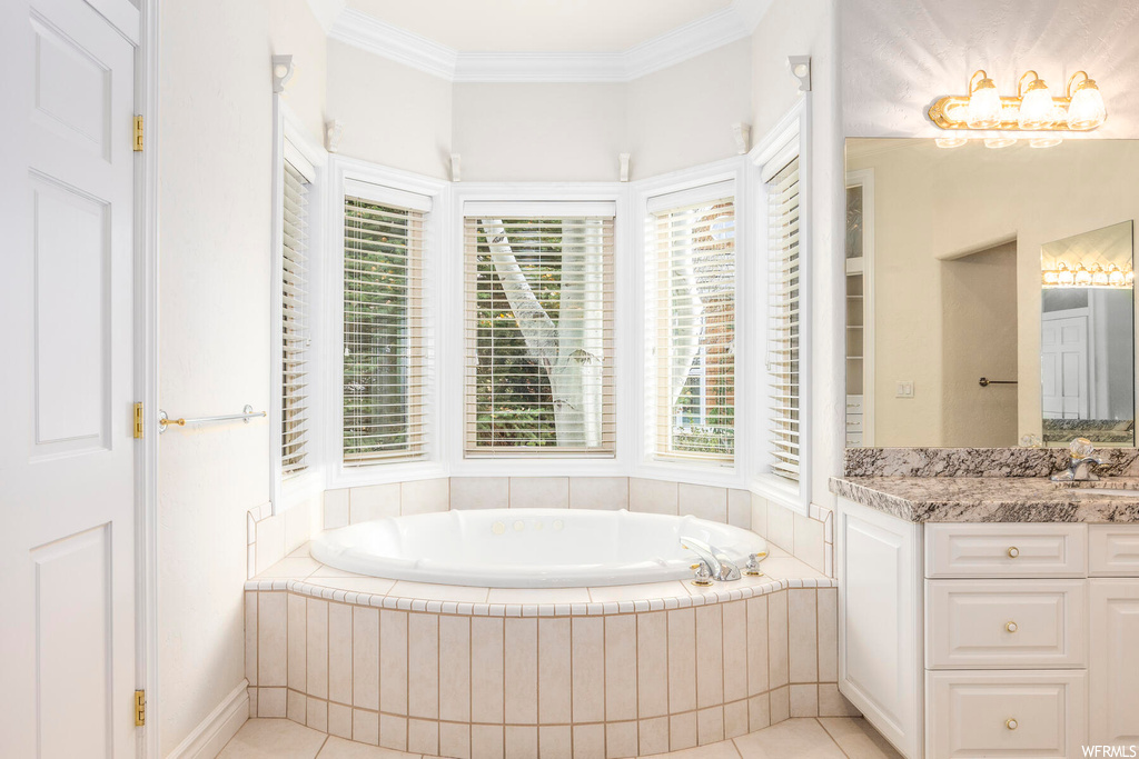 Bathroom featuring tile flooring, a wealth of natural light, tiled tub, and vanity