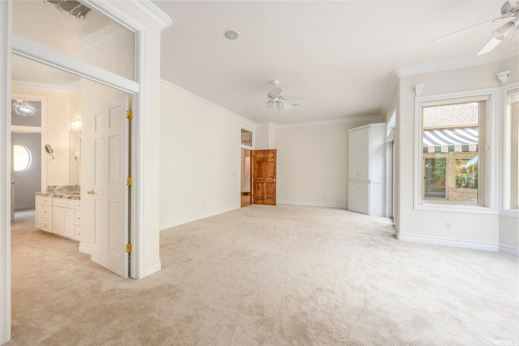 Spare room with ceiling fan, light colored carpet, and crown molding