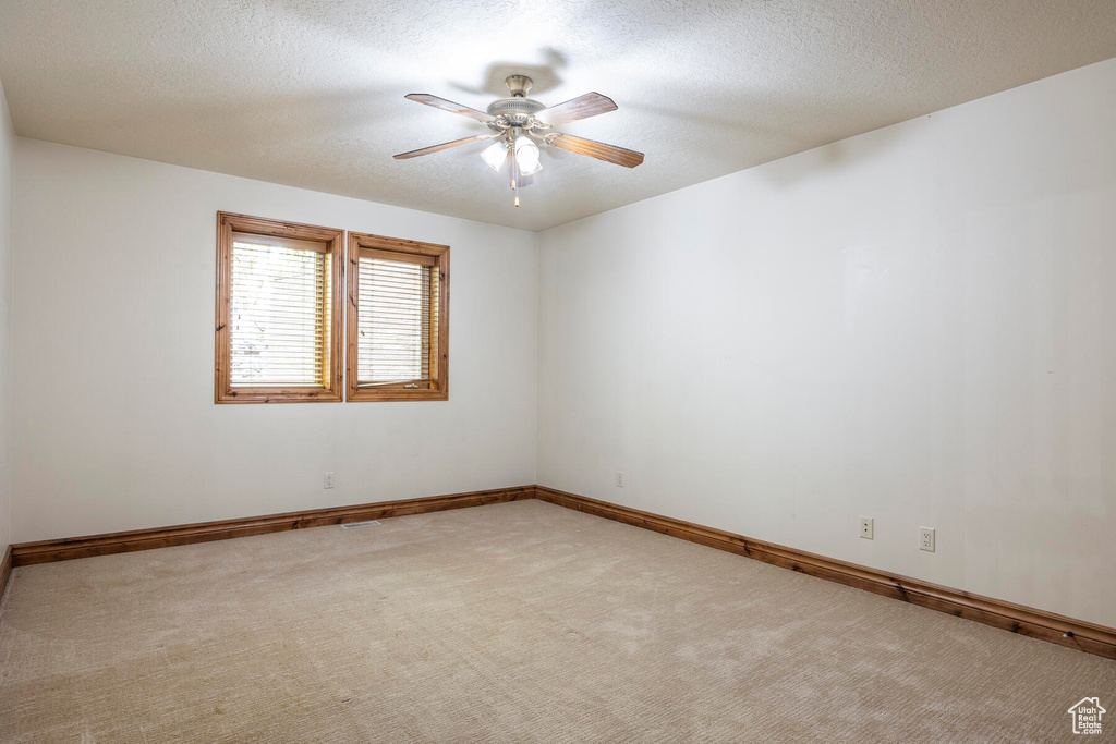 Unfurnished room with light carpet, a textured ceiling, and ceiling fan