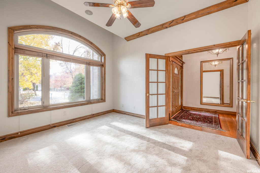 Unfurnished room with lofted ceiling, light carpet, ceiling fan, and french doors