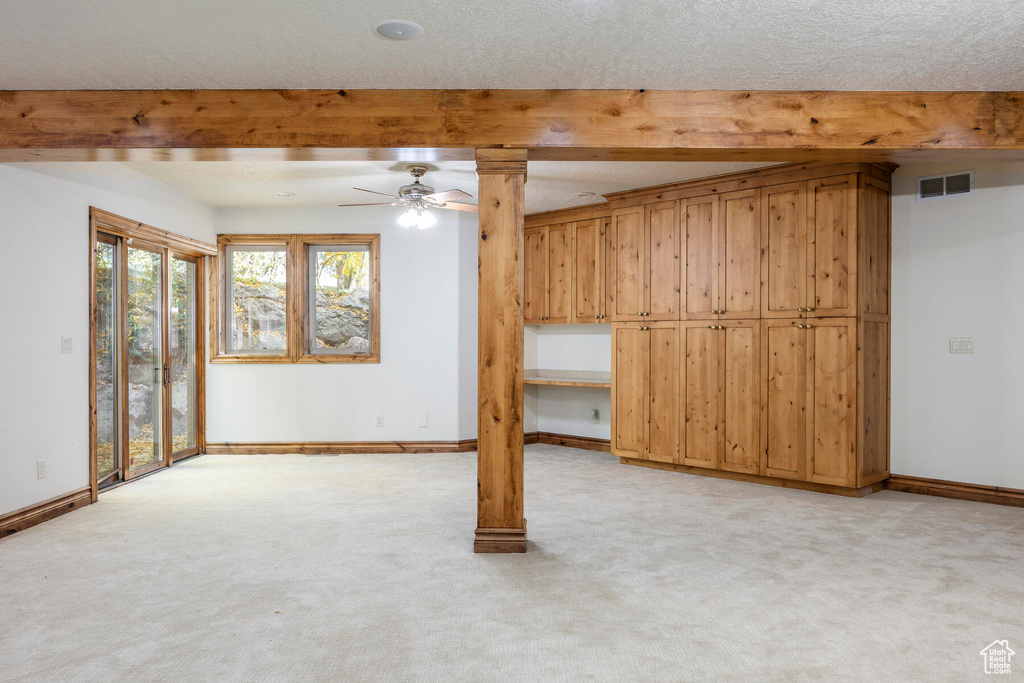 Basement with light colored carpet, ceiling fan, and a textured ceiling