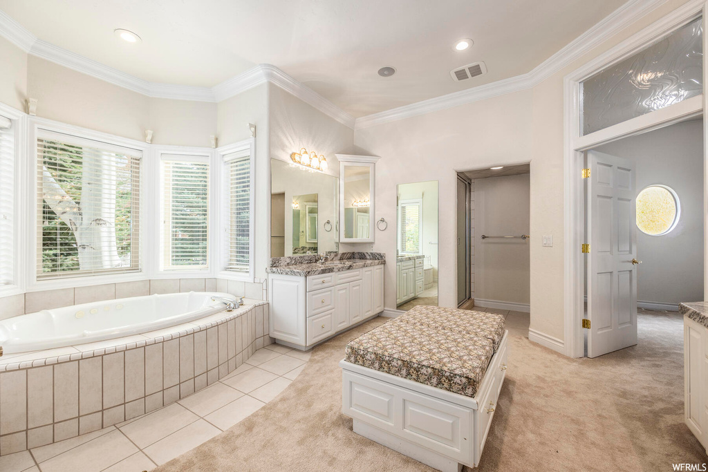 Bathroom with vanity, ornamental molding, tile floors, and a relaxing tiled bath