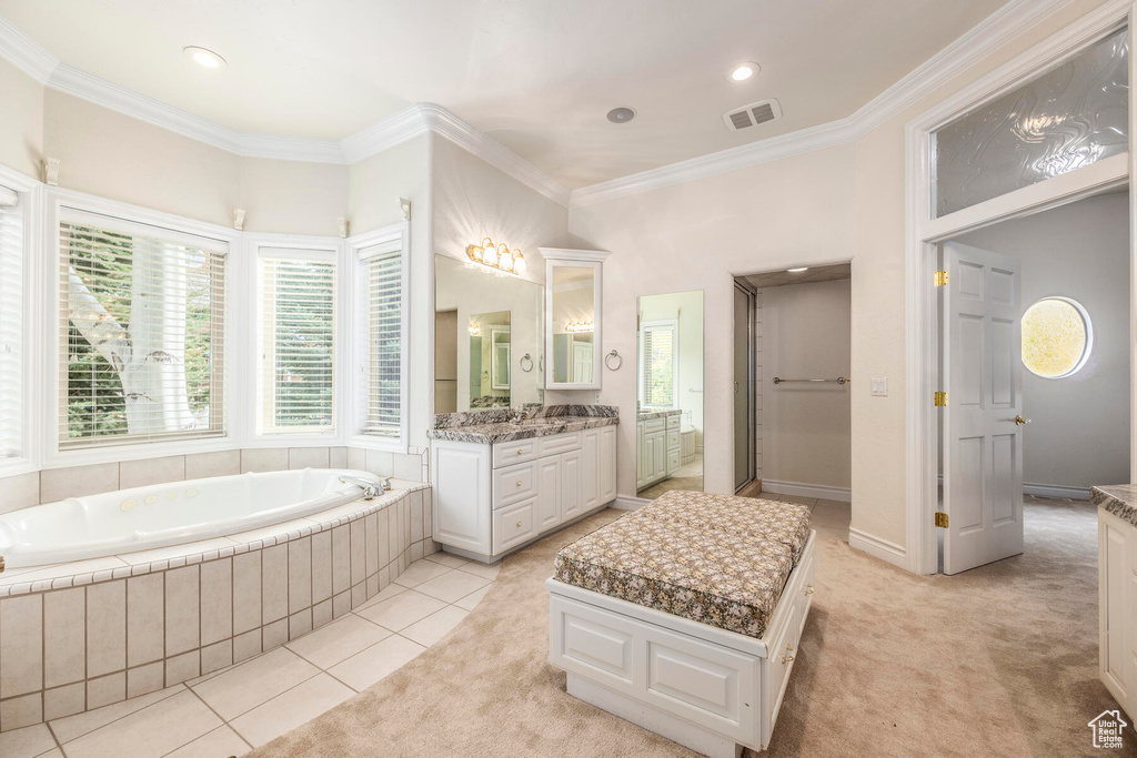 Bathroom with tile floors, a relaxing tiled bath, ornamental molding, and vanity