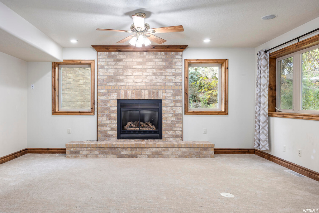 Unfurnished living room with a healthy amount of sunlight, a fireplace, and carpet