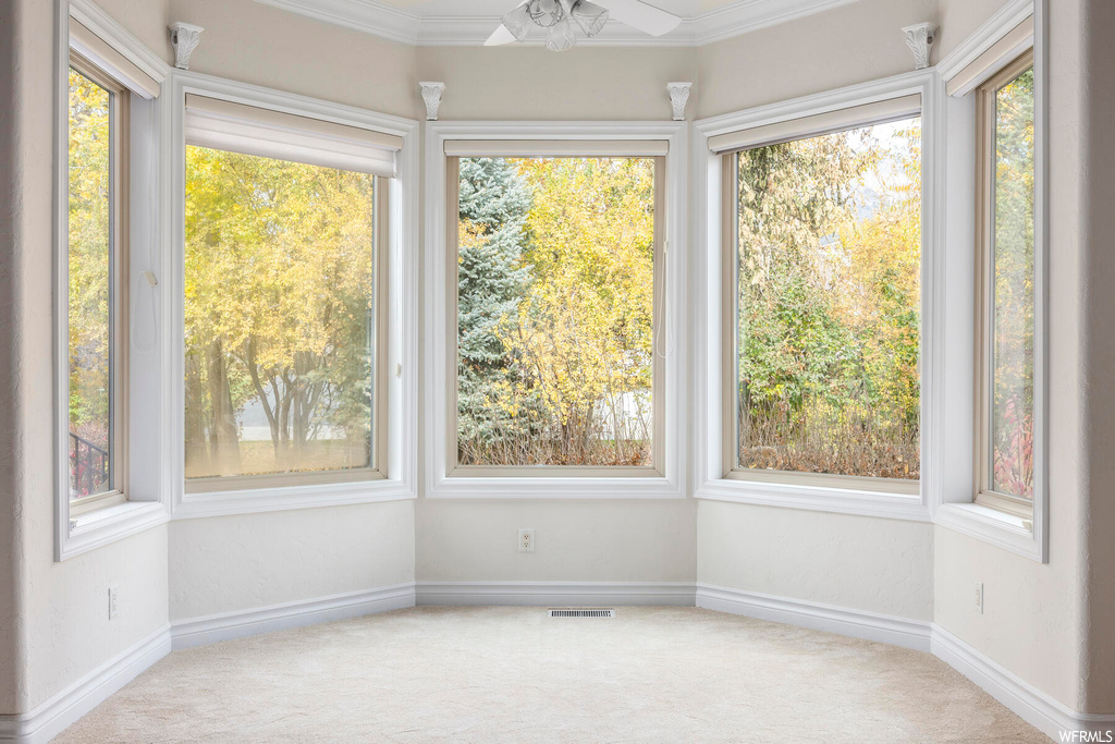 Unfurnished sunroom with ceiling fan and a wealth of natural light