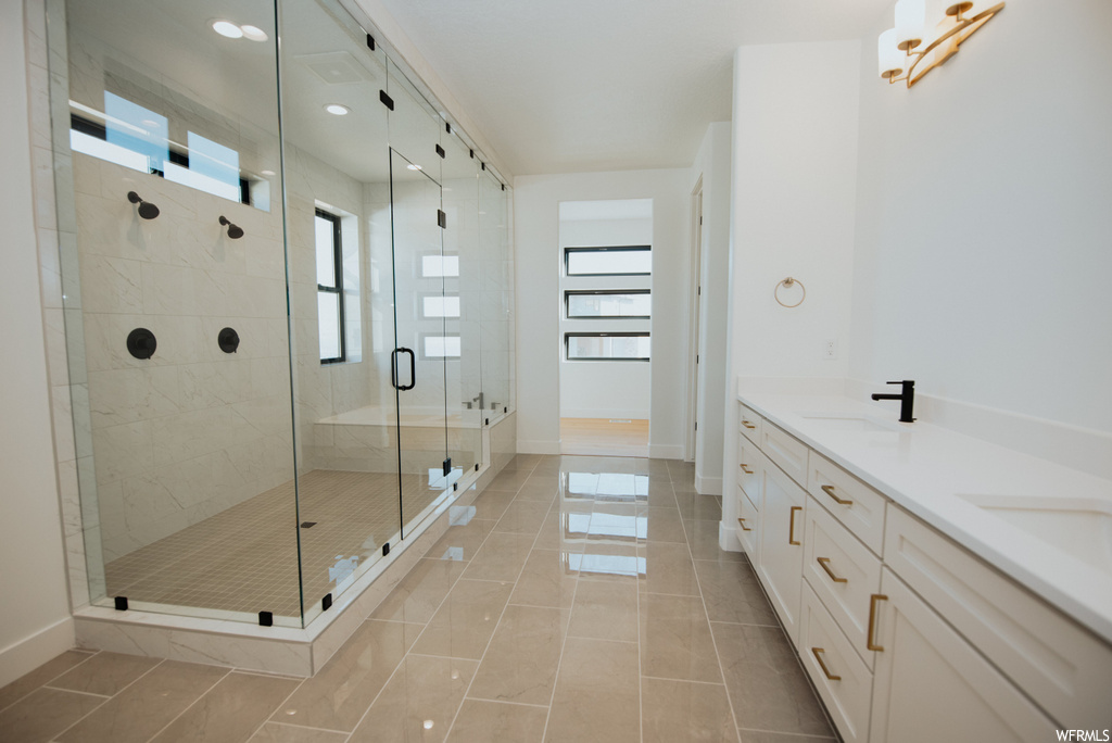 Bathroom featuring tile flooring, double sink vanity, and shower with shower door